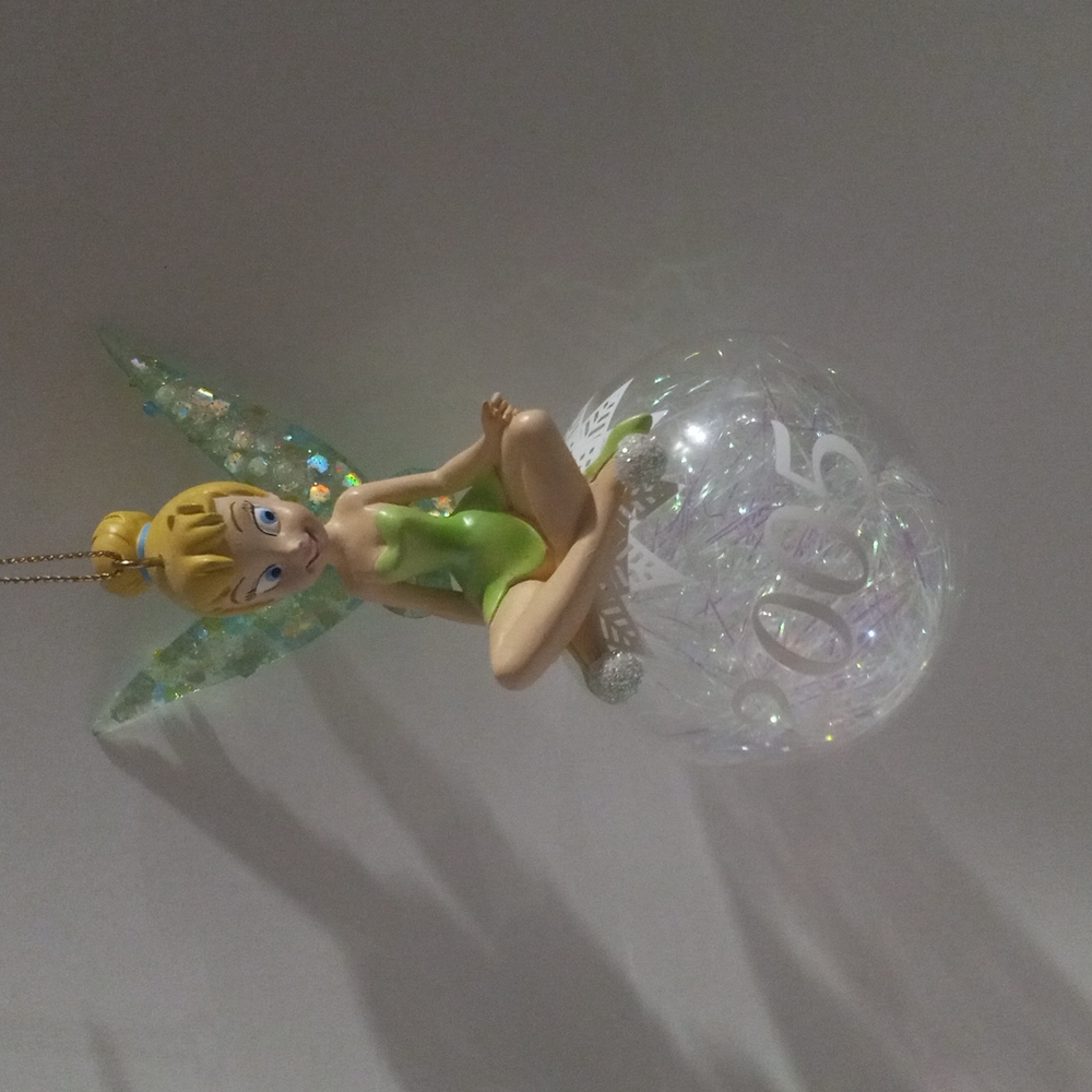 Tinkerbell sitting on a plastic ball with glitter ribbon and 2005 on it